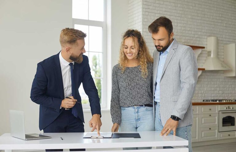 Homebuyers review a purchase offer and inspection documents at a kitchen table with a calculator and pen.